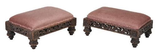A pair of Anglo-Indian footstools, circa 1830, each upholstered seat above a profusely carved and