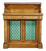 A George IV pollard oak side cabinet, circa 1825, with an upper shelf above a frieze drawer and a