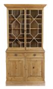 A pine cabinet bookcase, 18th century and later elements, the moulded cornice and dentil frieze