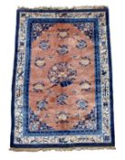 A Chinese rug, the terracotta field decorated with decorative roundels in blue tones,