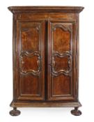 A Louis XV walnut armoire, circa 1750, the moulded frieze, above a pair of multi panelled and