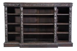 A Victorian oak breakfront open bookcase, circa 1880, the shaped top with acanthus carved edge,