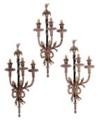 A set of three ebonised and gilt metal three light wall appliques in the Louis XVI style, early