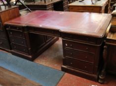 A mahogany twin pedestal partners desk with tooled red writing surface, with nine drawers and three