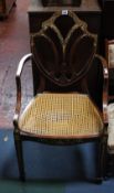 A polychrome decorated mahogany elbow chair with a cane seat and loose cushion  Best Bid