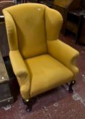 A Georgian style wing chair, upholstered, and on cabriole legs joined by stretchers