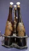 Three brown glass bottles painted with `Rum`, `Whiskey` and `Gin` amongst fruiting vines, each with