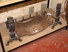 An iron fire grate with cast andirons in the form of lions in seated pose