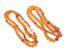 Two amber bead necklaces, the first consisting of seventy 7 Two amber bead necklaces, the first