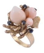 A coral and sapphire dress ring, the cowrie shell shaped coral set amongst... A coral and sapphire