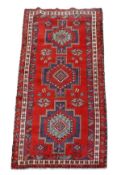 A Shiraz carpet, the red field decorated with geometric medallions and borders in green, navy and