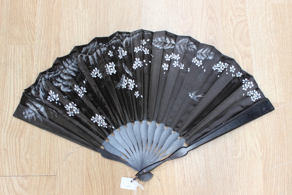 An early 20th Century black silk fan, circa 1900-1906, hand painted with flowers, leaves and