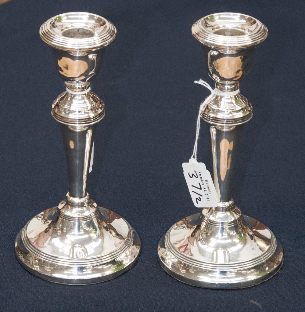 A pair of mid 20th century silver candlesticks, concentric band decoration to sconce, tops of