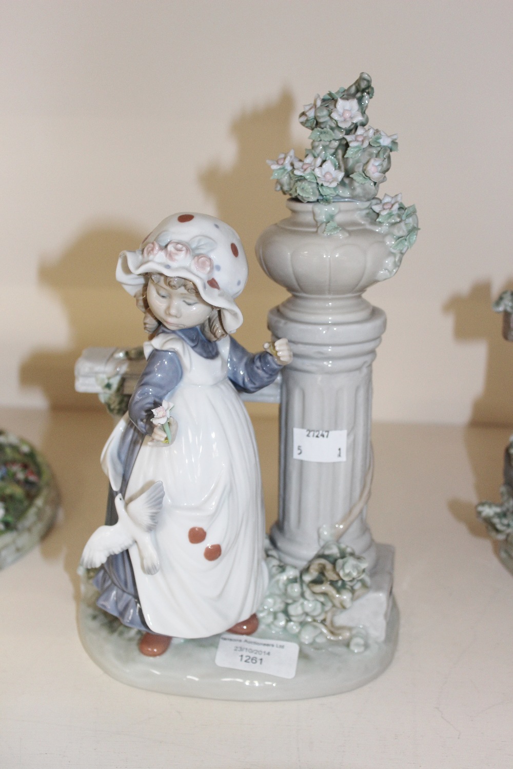 A Lladro girl with flowers and birds by pillar