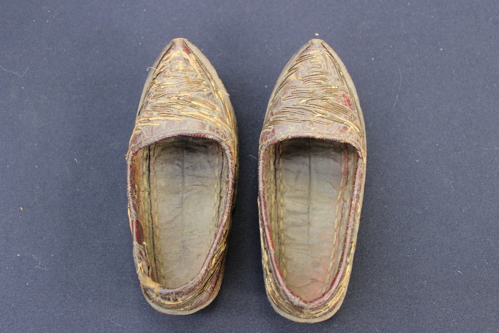 A pair of late 19th Century Burmese child's shoes, made from red leather and decorated with simple