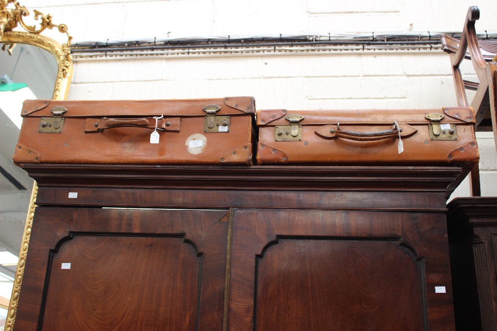 Two tan cow hide vintage suitcases (2)