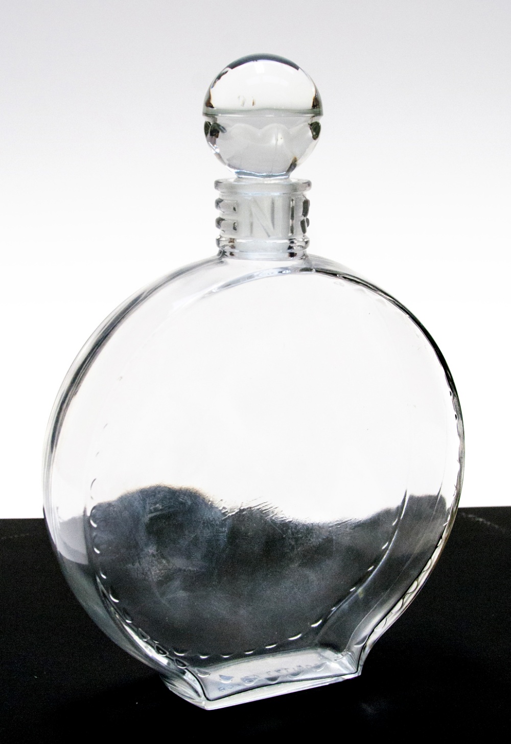 A Lalique Nina Ricci perfume decanter, plain circular form with crescent moulded border and