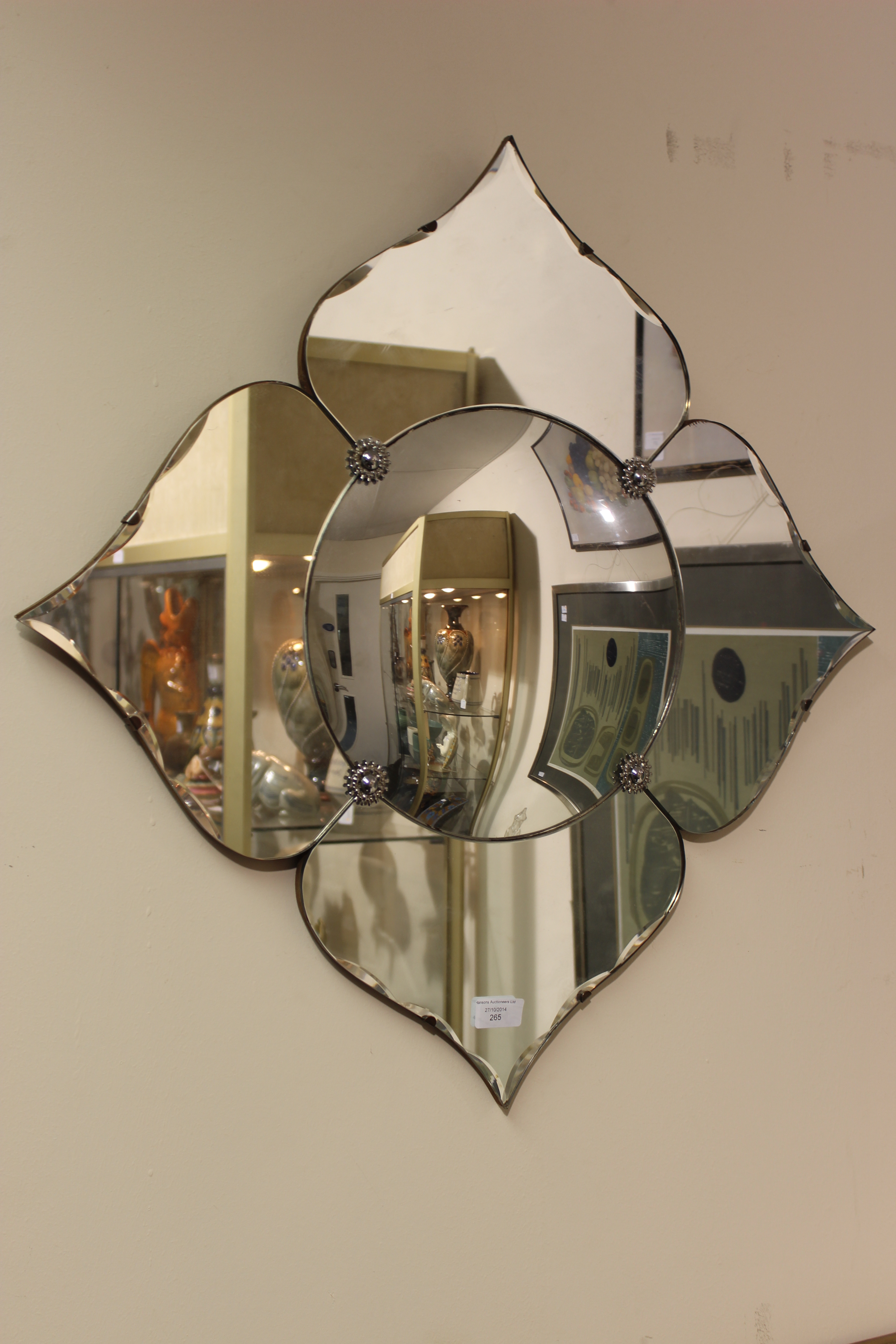 An Art Deco wall mirror of flower shape, the convex centre surrounded by ogee petals fixed with