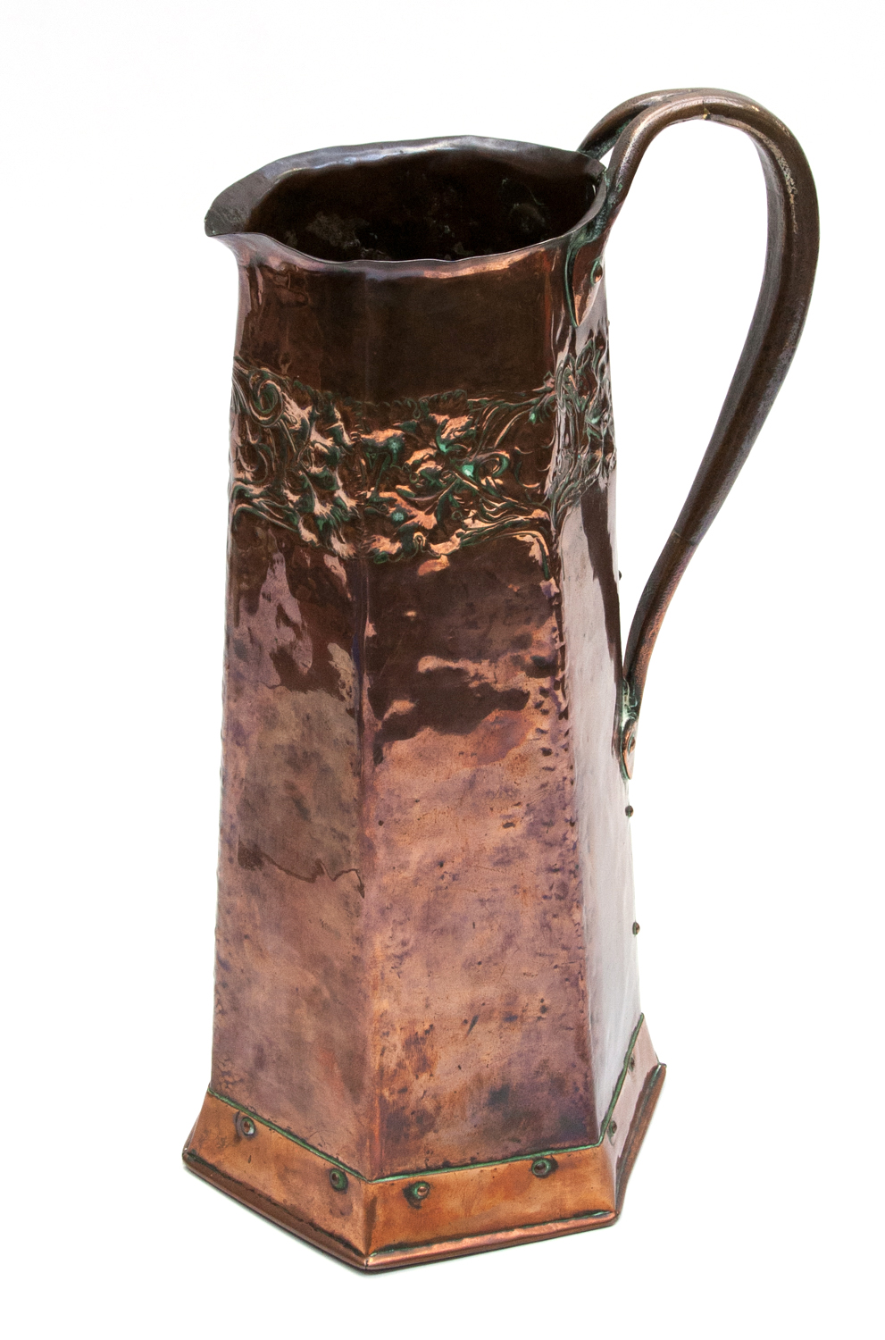 An Arts and Crafts Keswick School copper jug, octagonal tapered form with repouse foliate banding