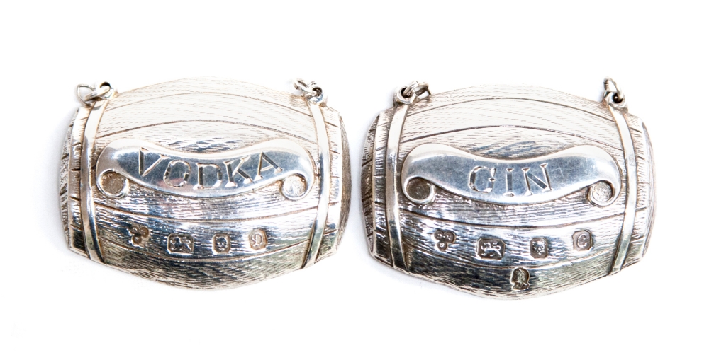 A pair of modernist silver wine labels, each cast in the form of a barrel, one reading 'Vodka',