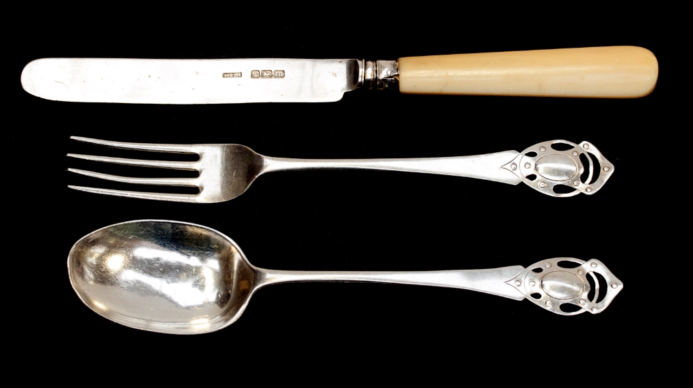 An Arts and Crafts silver christening set, comprising spoon fork and knife, plain form with