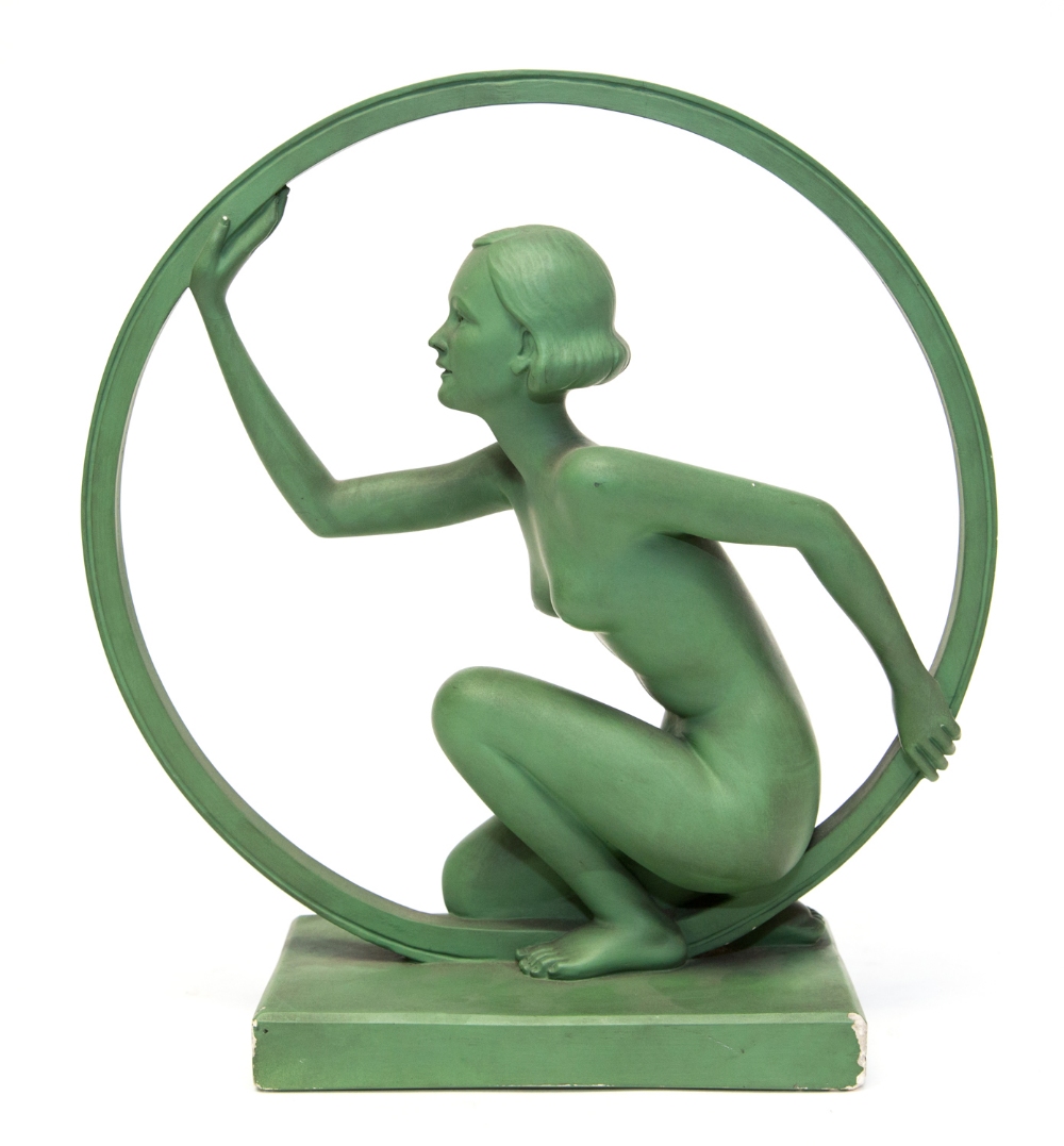 An Art Deco plaster figure of a female nude crouching inside a hoop on a rectangular base,