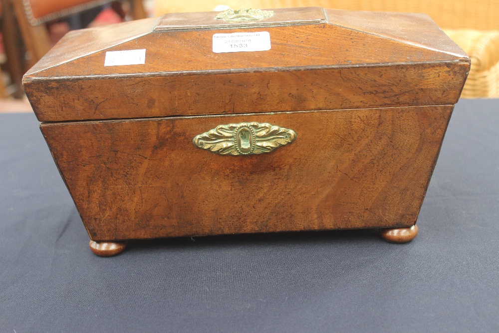 An early 19th century mahogany sarcophagus shaped tea caddy, the top with a brass mount, the front