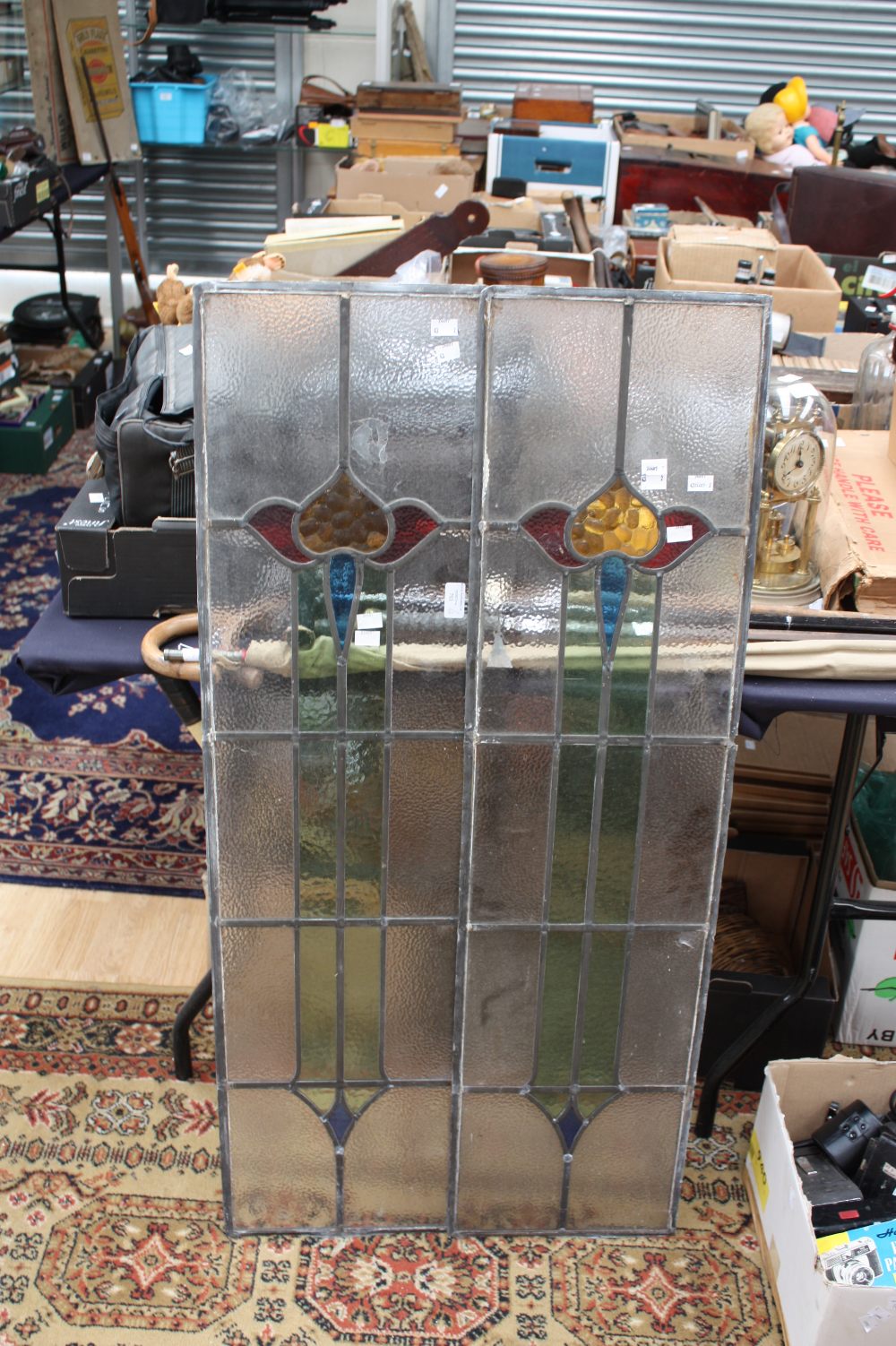 A pair of early 20th Century leaded glass panels of Arts and Crafts style with central coloured