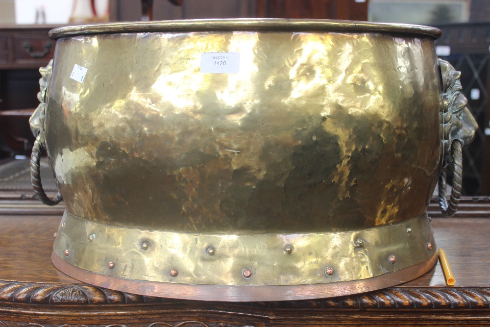A large brass oval log bucket with lion mask handles