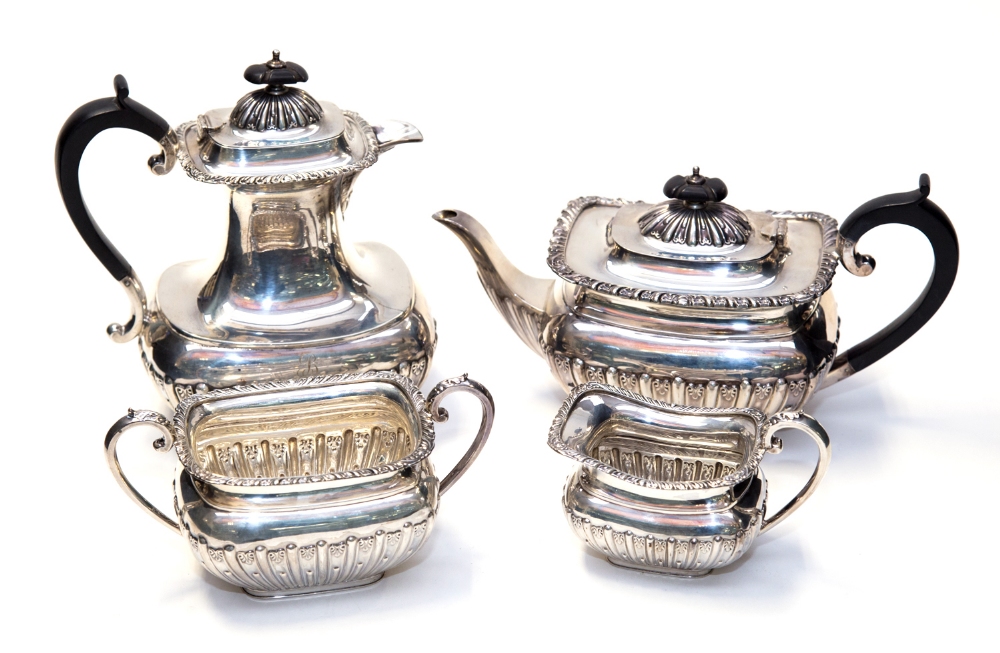 A George V silver four piece tea set, of square section ogival form, the lower sections reeded, with