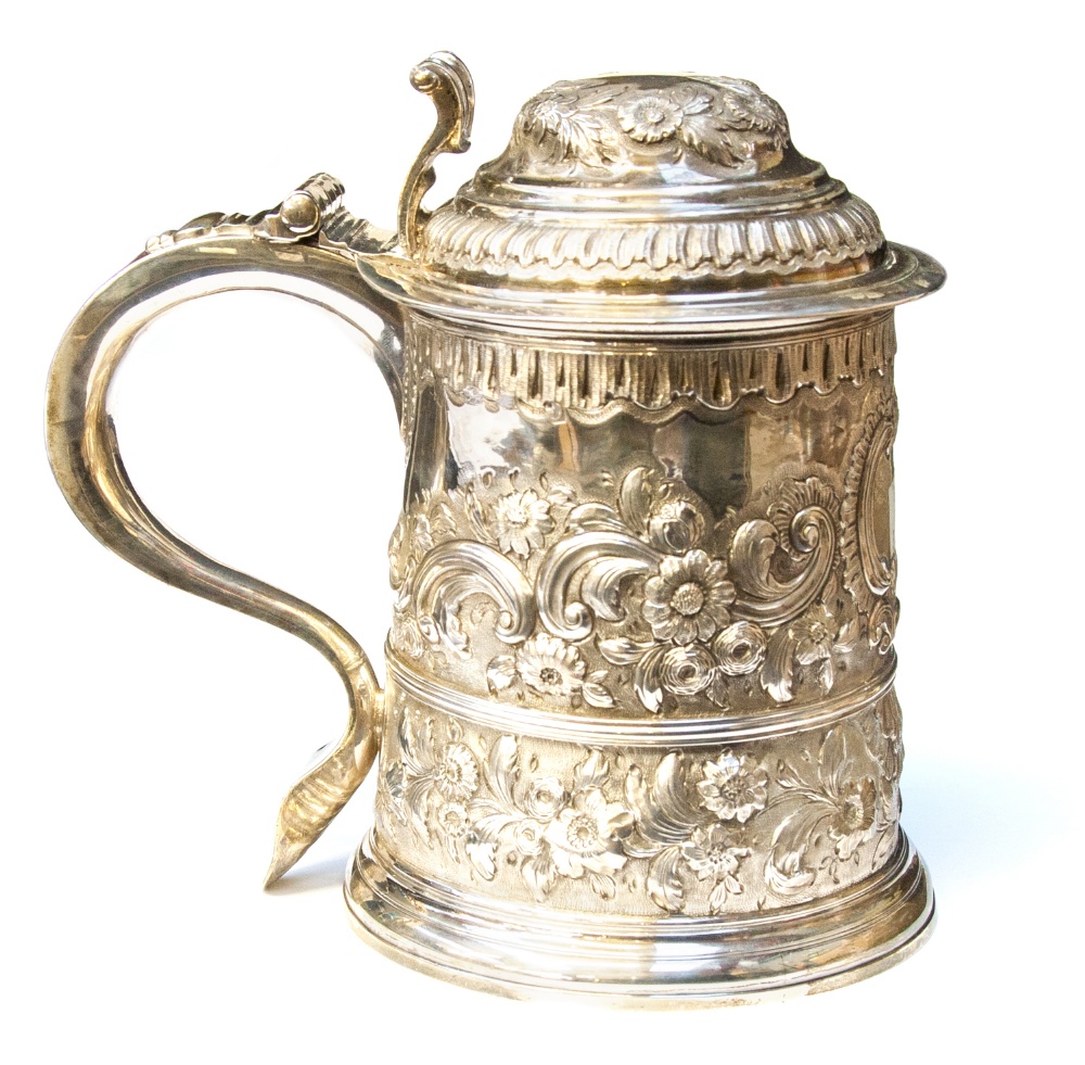 A George III silver lidded tankard, turned cylindrical form, later embossed and engraved with floral