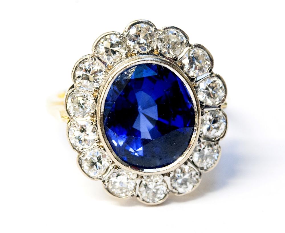 An 18ct gold oval cluster ring, set with blue sapphire approx 8.25ct, surrounded by brilliant cut