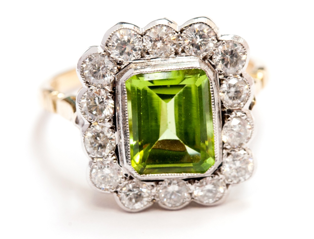 A peridot and diamond ring, centred with step-cut stone approx 0.90ct, surrounded by fourteen