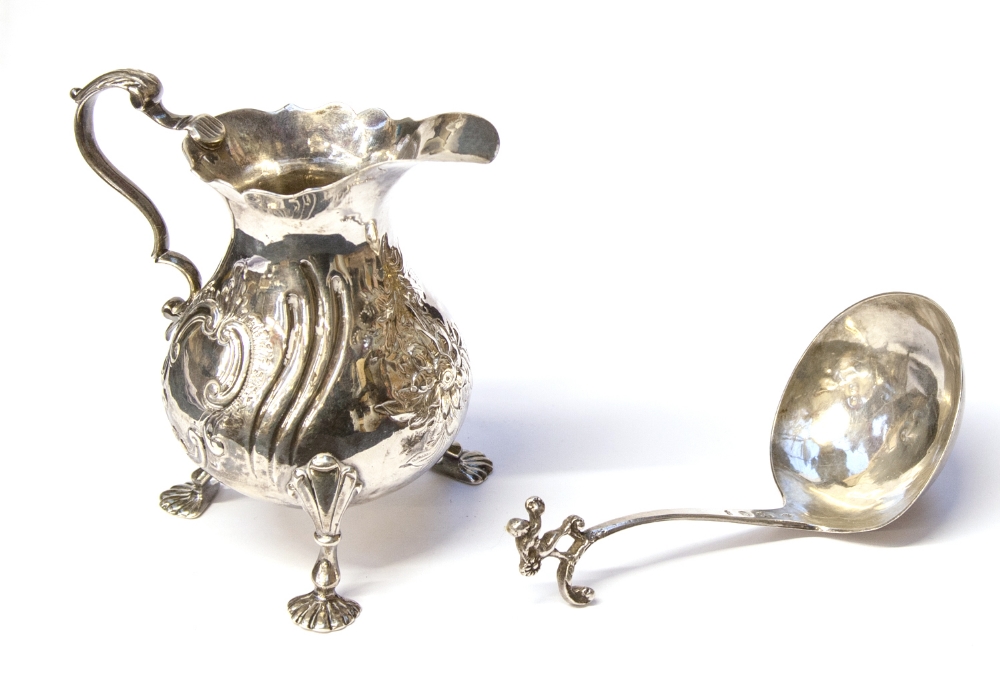 A George II silver cream jug, baluster form on three shell feet with ear scroll handle, later