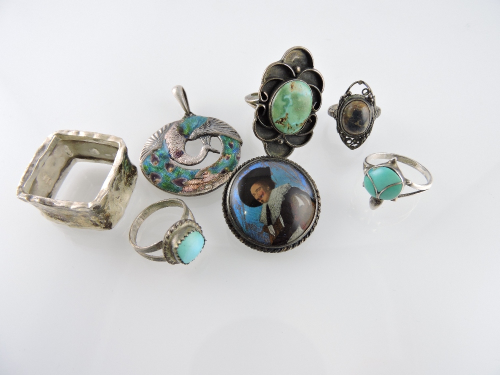 A collection of four silver rings, two set with turquoise and two with agate, a circular brooch with