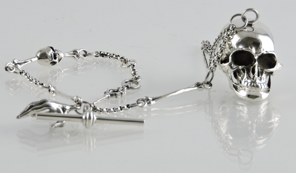 A cast silver skull pill box on chain, hung watch key and hand fob.
