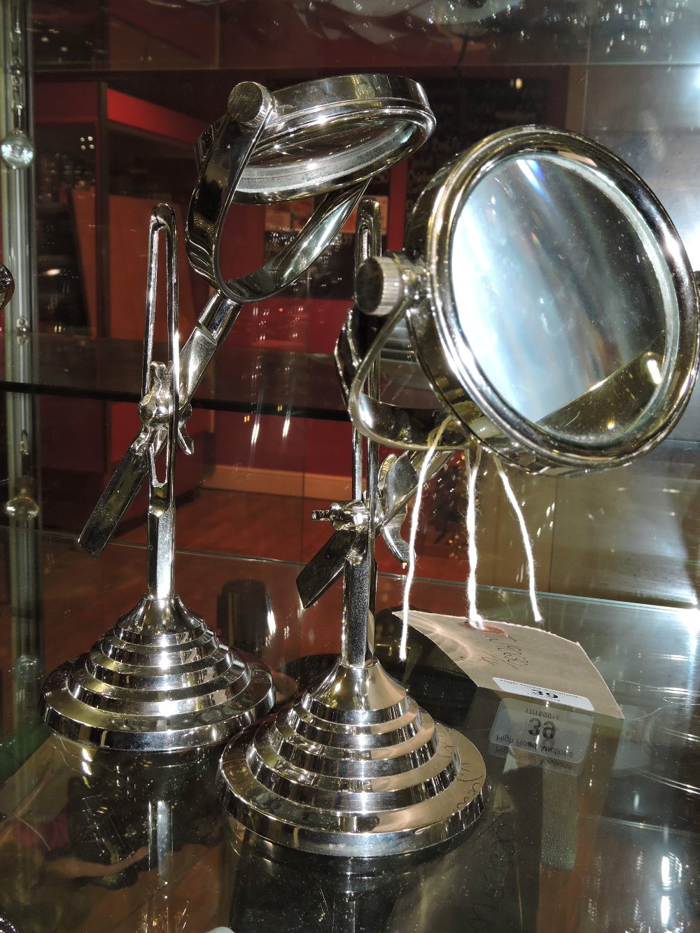 A pair of plated adjustable magnifying glasses, on stepped circular bases.