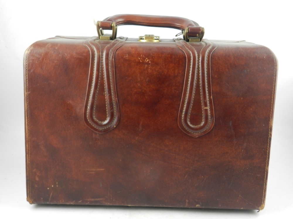 A tan leather gladstone bag, having brass handles and clasp.