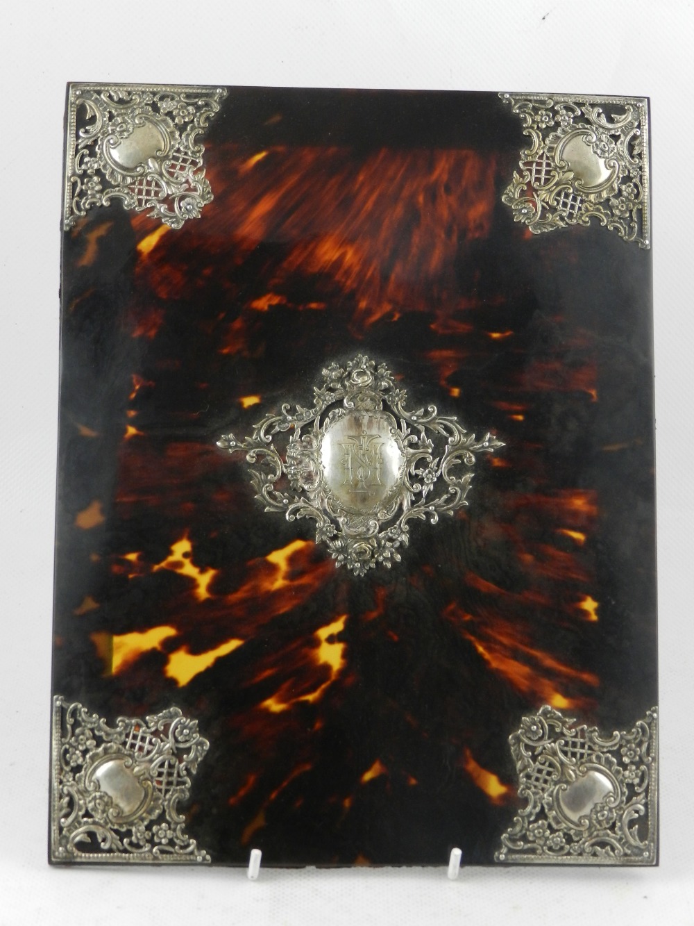 A late Victorian silver mounted tortoise shell blotter cover, centred with a monogrammed foliate