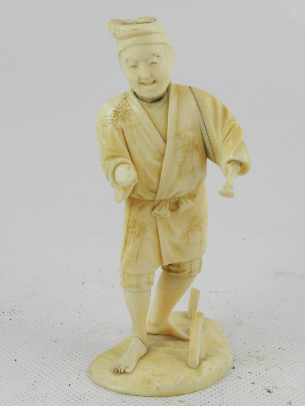 A Japanese Meiji period carved ivory okimono, study of a pastoral gentleman on naturalistic base.