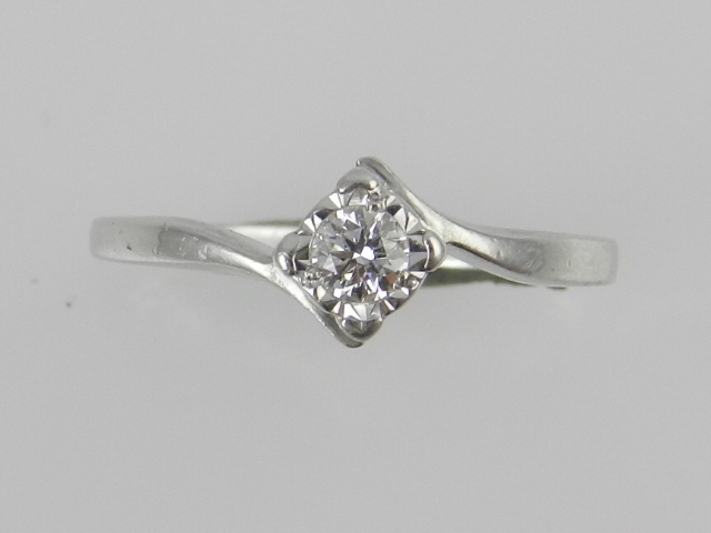 A 9ct white gold solitaire diamond cross over ring, centred with an illusion set brilliant cut