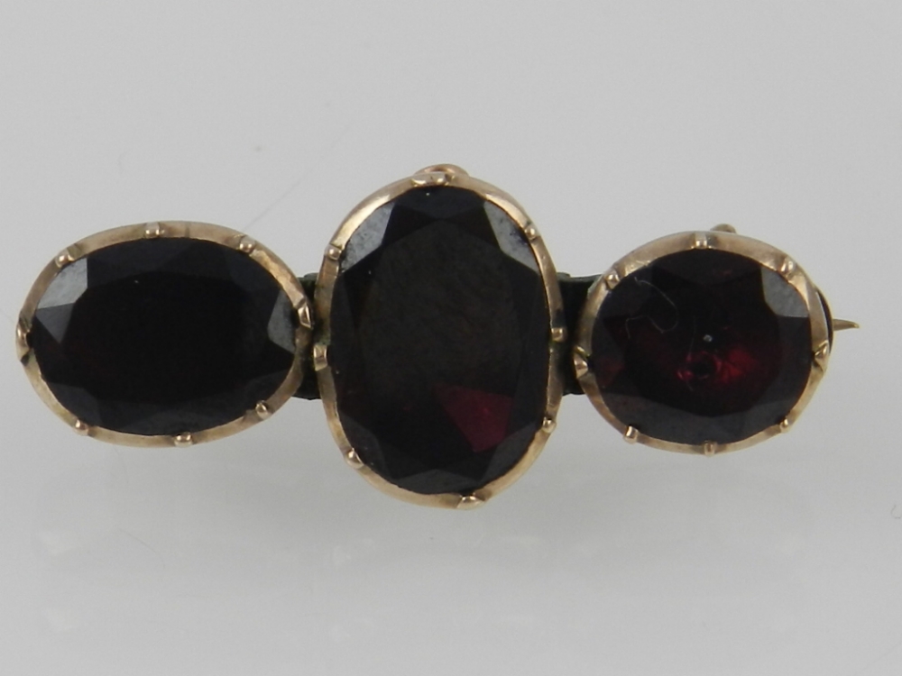 A Victorian yellow metal and garnet three stone bar brooch