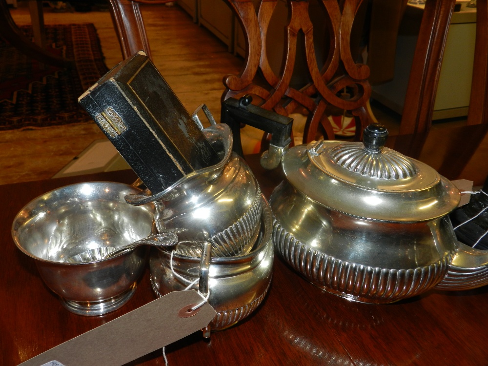 An Edwardian three piece silver plated tea service of boat form, with demi lune embossed decoration,