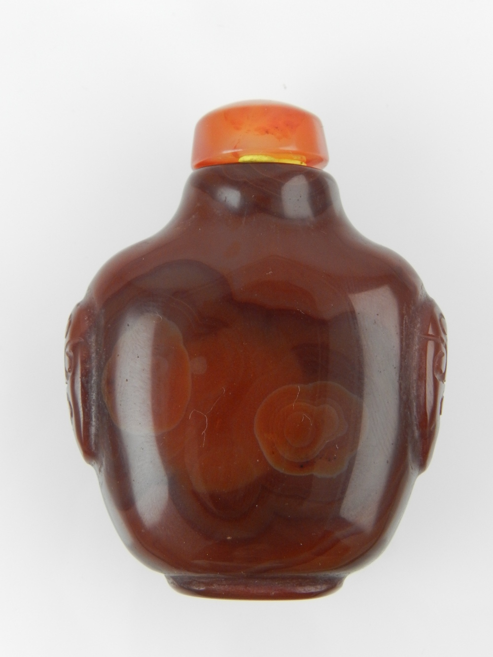 A Chinese carved orange agate scent bottle, with cabouchon stopper, the baluster body decorated with