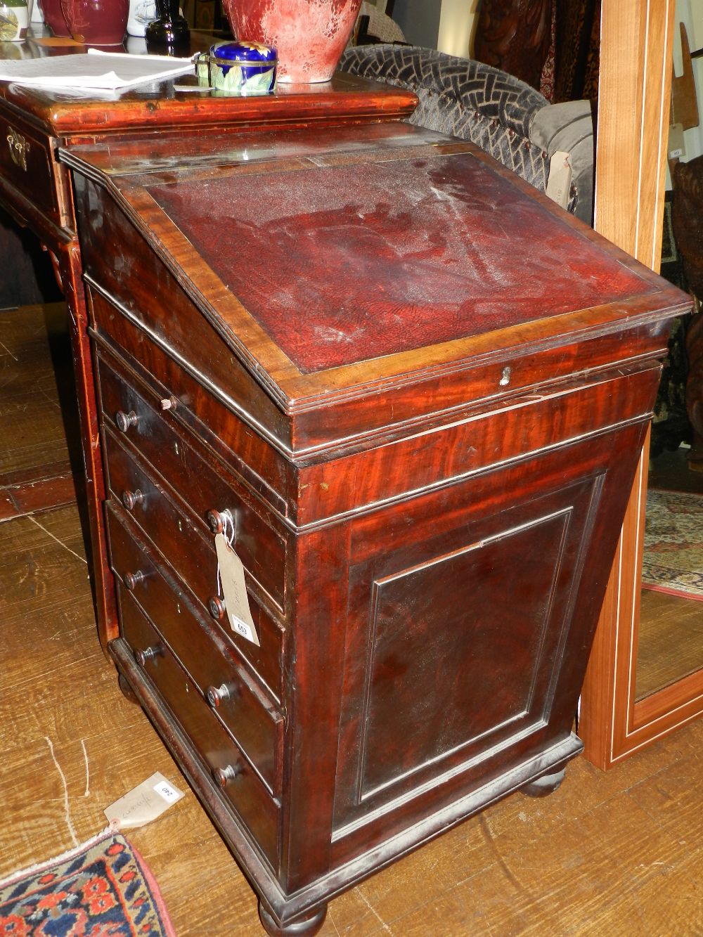 In the manner of Gillows. A William IV mahogany davenport desk, the hinged top with red skiver,