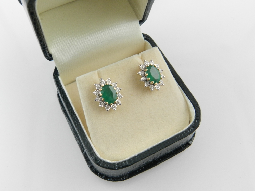 A pair of 18 carat yellow gold emerald and diamond cluster earrings.