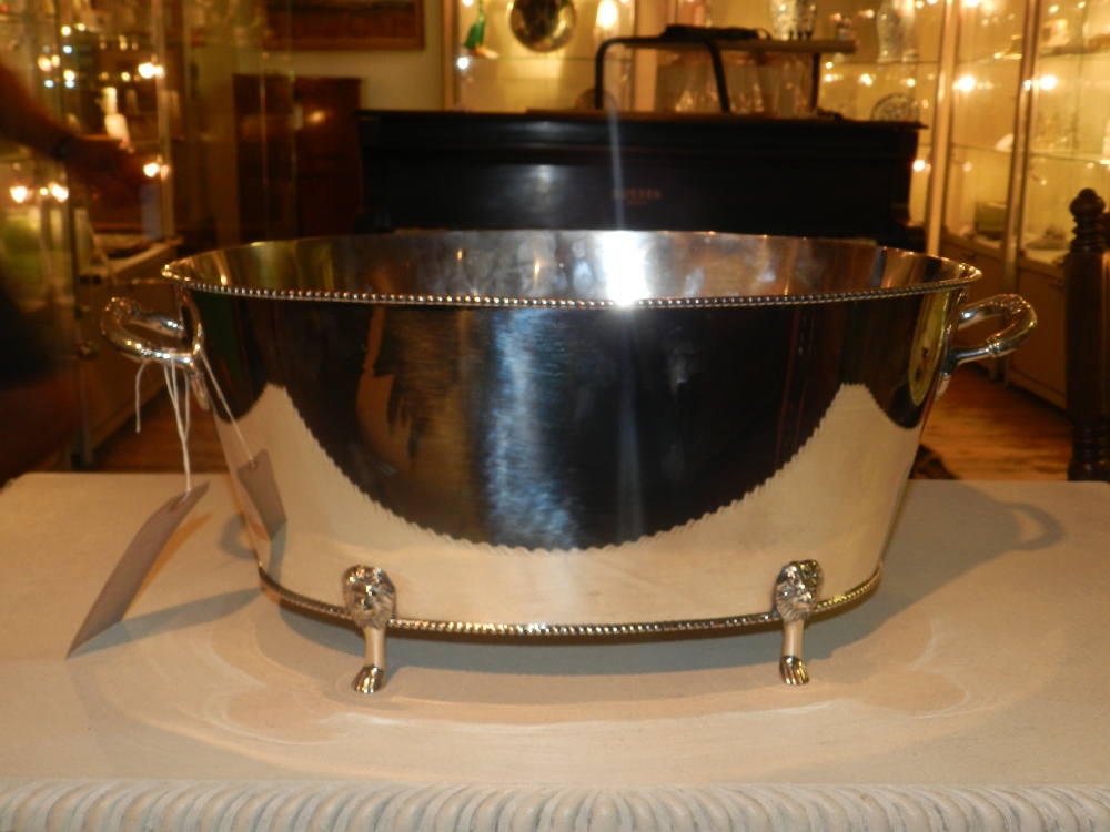 A silver plated twin handled champagne bath, oval form, having beaded boarder and raised on four