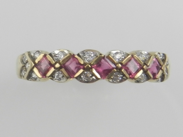 A 9ct yellow gold ruby and diamond dress ring, set lozenges cut rubies within diamond reserves.