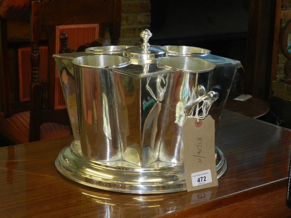 A silver plated four bottle wine cooler, having central reservoir, raised on a stepped circular