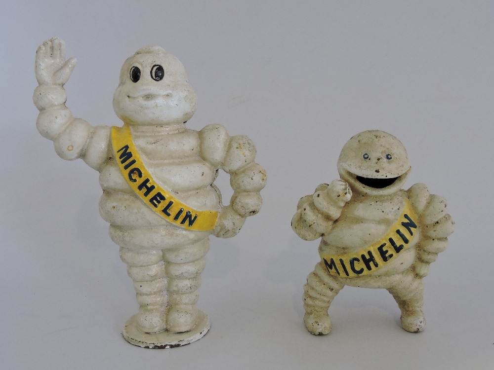 Two cast metal Michelin Man figures.